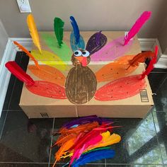 a cardboard box filled with colorful feathers and a turkey