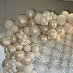 a bunch of balloons that are hanging from the ceiling in front of a tiled wall