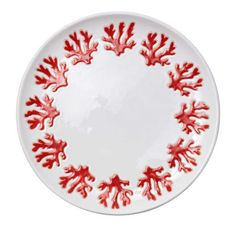 a white plate with red corals painted on the rim and bottom, sitting in front of a white background