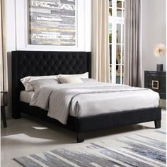 a bedroom with a bed, night stand and rugs on the floor in front of it