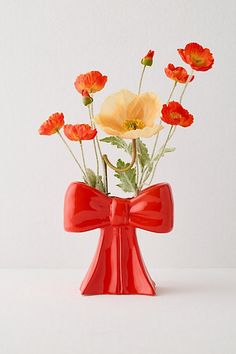 a red vase filled with flowers on top of a table