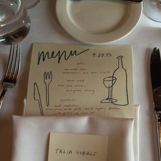 a place setting with menus and silverware on a white tableclothed table