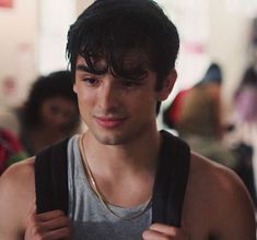 a young man is looking at the camera while wearing a tank top and gold necklace