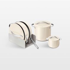 a white kitchen set with pots and pans next to each other on a gray background