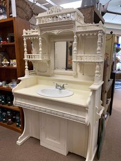 a white sink sitting under a mirror in a room filled with shelves and other items