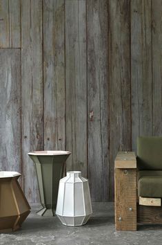 three different colored vases sitting in front of a wooden wall