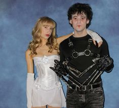 a man and woman dressed up in costume posing for a photo with one holding an arm around the other's shoulder