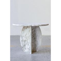 a marble table sitting on top of a floor next to a white wall in a room