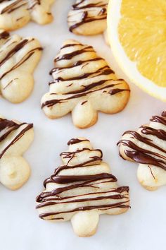 cookies with chocolate drizzled on them next to an orange and lemon slice