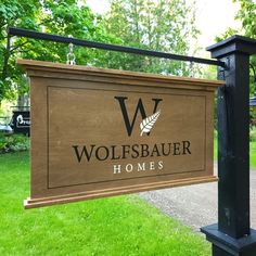 a sign that says wolfsbauer homes in front of some grass and trees