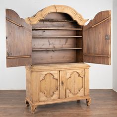 an old wooden cabinet with two doors and cupboards on the top, sitting in a wood floored room