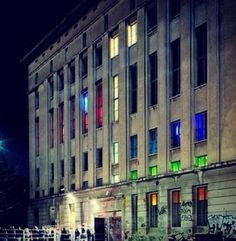 an old building with graffiti on the side and windows lit up by street lights at night