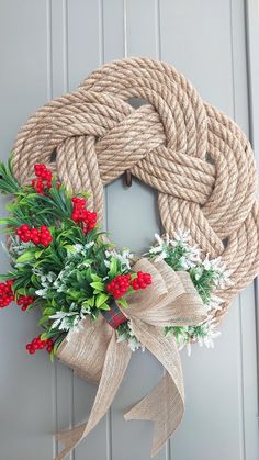 a wreath with red flowers and greenery tied to it