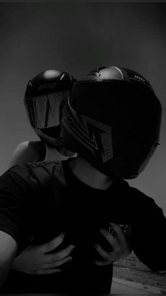 two people wearing helmets are hugging each other