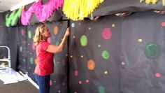 a woman is painting a wall with colorful streamers and pom - poms