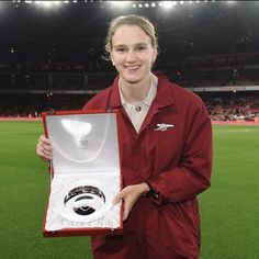 a woman holding an award in front of a stadium