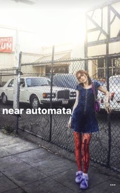 a woman standing in front of a fence with her hand on her hip and the words near automata