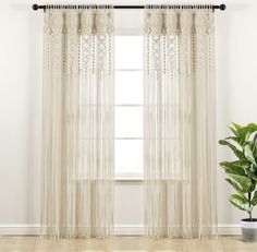 a white curtain hanging on the side of a window next to a potted plant