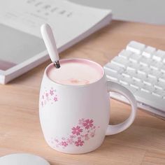 a coffee mug with a spoon in it sitting on a desk next to a keyboard