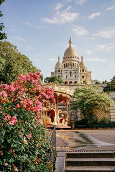 an old fashioned merry go round in front of a building with pink flowers on the steps