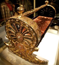 an elaborately designed bed with gold paint and jewels on the headboard is displayed in a glass case