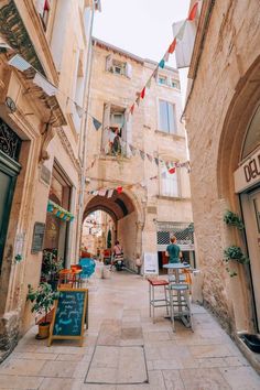 an alley way with shops and flags on the buildings