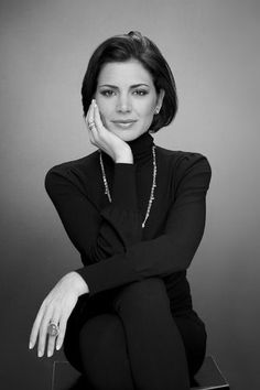 a black and white photo of a woman with her hand on her chin, posing for the camera