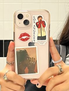 a woman holding up her phone case with stickers on it