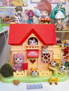 there is a small toy house with many animals around it and toys on the table