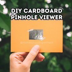 someone holding up an orange piece of paper with the words diy cardboard pinhole viewer