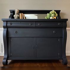 a black dresser with flowers and books on top