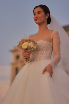 a woman in a wedding dress holding a bouquet and looking off to the side with her hand on her hip