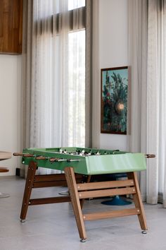 a foosball table in the middle of a room with curtains on the windows