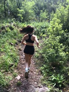 a woman running down a trail in the woods