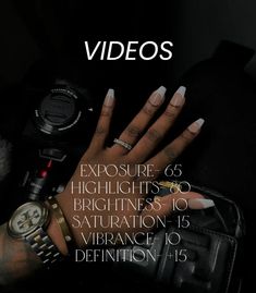 a woman's hand with white nails holding a camera and wrist watch in front of her