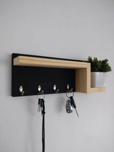 a wooden shelf with key hooks and keys hanging from it's sides next to a potted plant