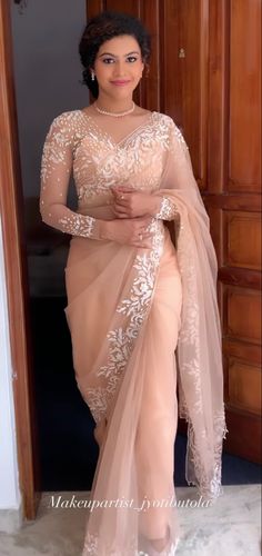 a woman in a beige sari posing for the camera