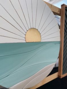 the sun is setting over the water on top of an ocean themed bed frame with blue and white sheets