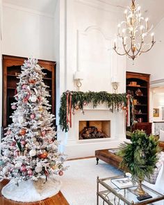 An elaborate garland hangs from the white chimney piece along with ribbons and ornaments in this traditional living room. To the side stands a frosted Christmas tree decorated with white and red baubles and ribbons...   Image: rachelfolkman