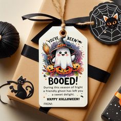 a gift wrapped in brown paper with a happy halloween tag attached to it and decorations around it