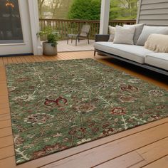 a living room area with couches and rugs on the wooden flooring outside