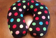 a black and multicolored polka dot donut pillow on a wooden table top