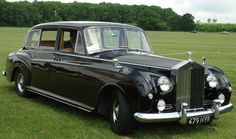 an old black car is parked in the grass