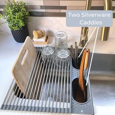 two silverware caddies sitting on top of a sink next to a wooden cutting board