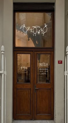 two wooden doors with glass on each side and white picket fence around them in front of a building