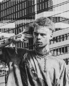 black and white photograph of a man with tattoos on his face, wearing chains around his neck