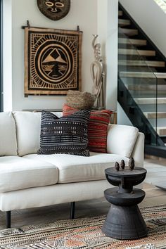 a living room filled with furniture next to a stair case and wall hanging on the wall