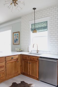 a kitchen with white brick walls and wooden cabinets, an area rug on the floor