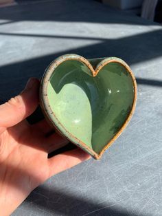 a hand holding a green heart shaped bowl