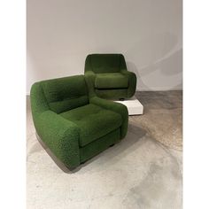 two green recliners sitting next to each other on top of a cement floor